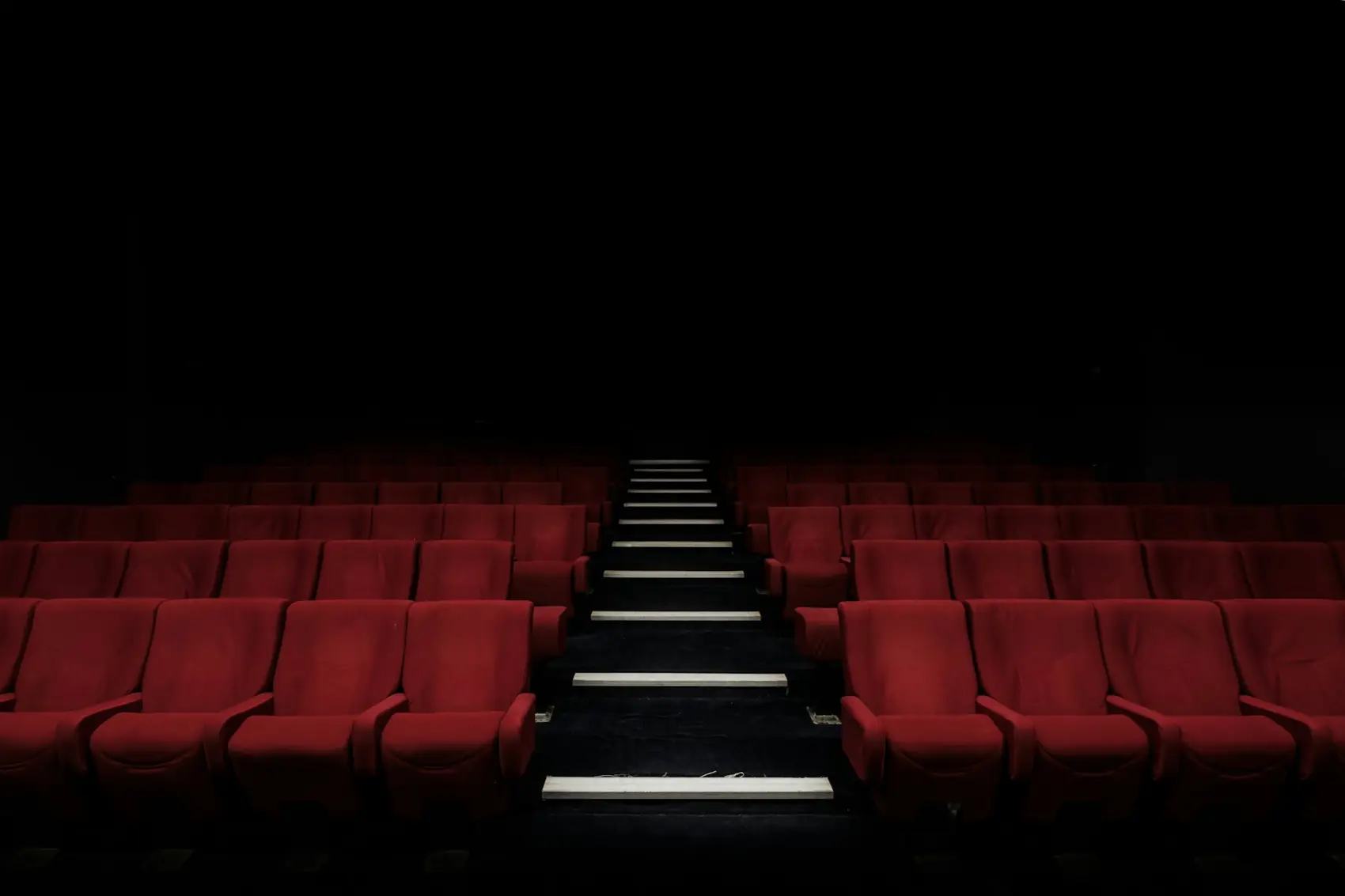 Butacas rojas de un cine vacío y a oscuras